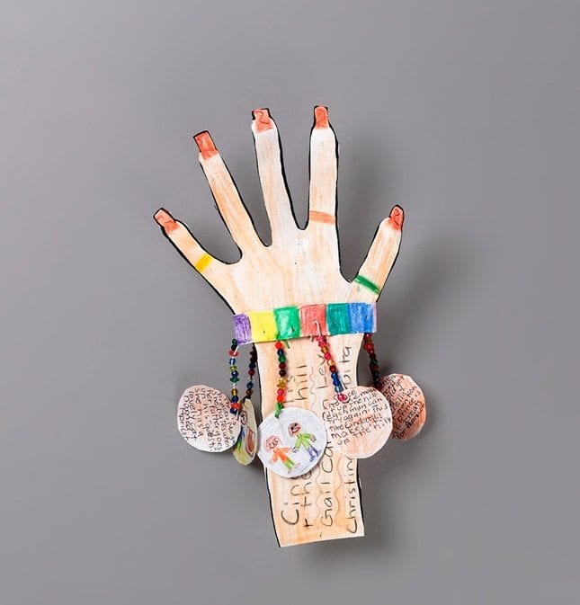 A adorn paper hand with paper charms hanging off of it